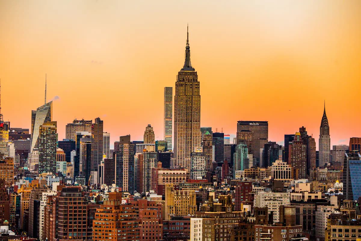 The Midtown skyline at sunset with the Empire State Building in the centre and the Chrysler Building to the right, under an orange sky
